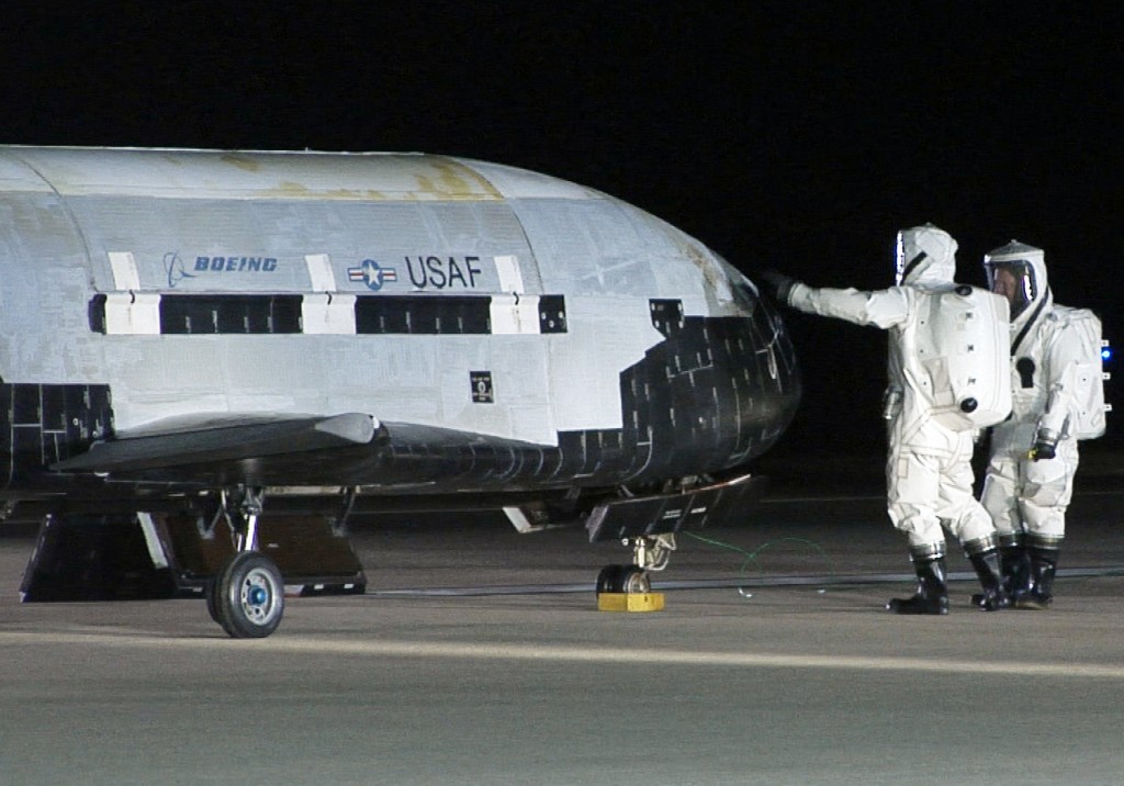 Personnel in protective  suits conduct checks on the US Air Force's first unmanned re-entry spacecraft.